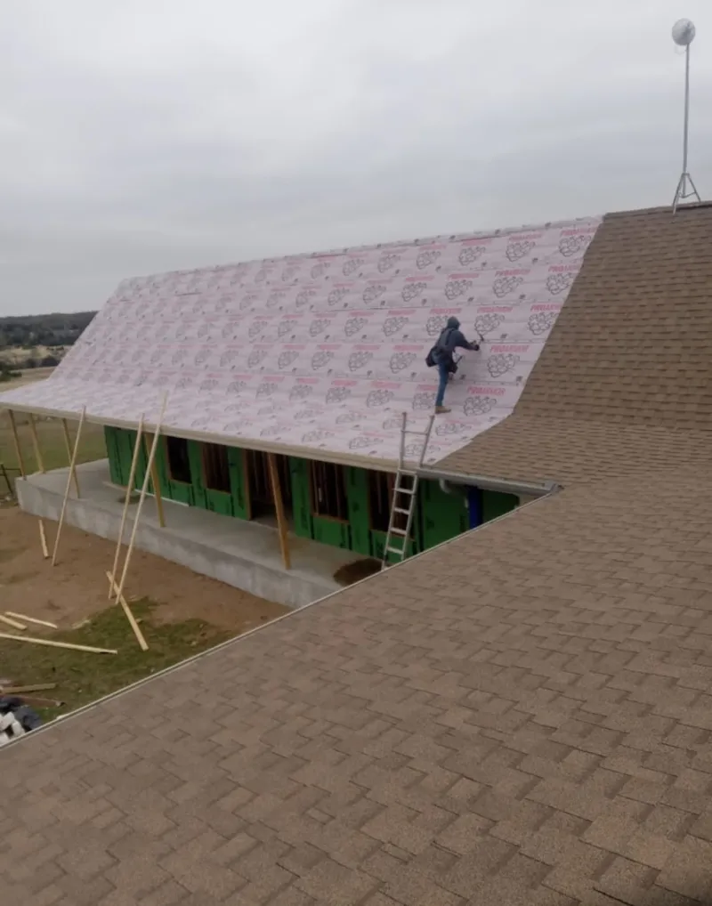 Worker preparing underlayment for a metal roof installation in University